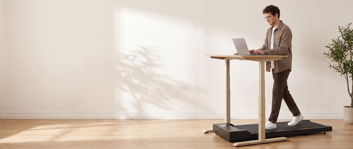 Man reading on a laptop while walking on a walking pad at a standing desk